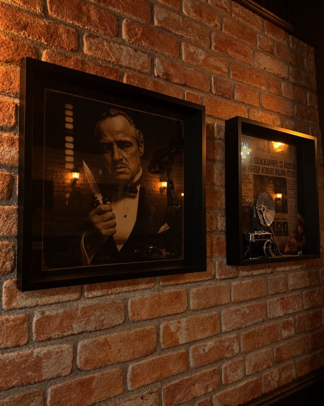 A framed black-and-white film portrait and an old newspaper front page on the brick wall